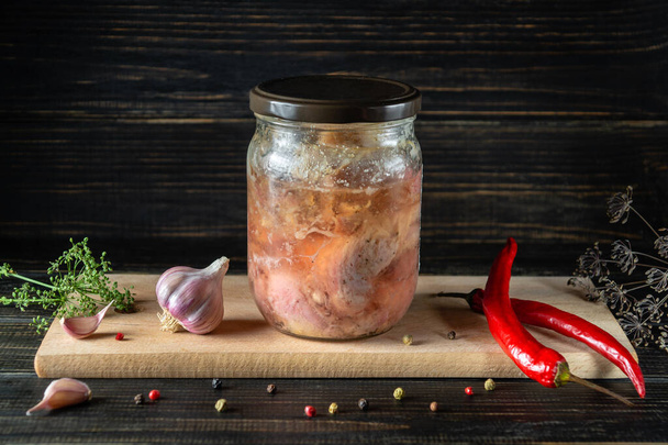 Canned meat or stew in a glass jar with spices on a cutting board. Stock of farm organic products. - Zdjęcie, obraz