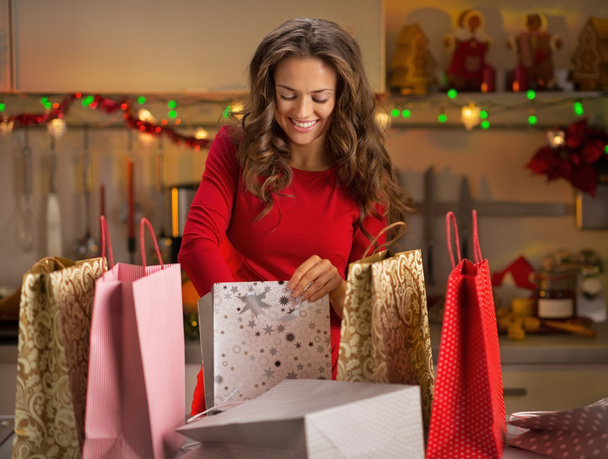 Smiling young woman with shopping bags in christmas decorated ki - Foto, afbeelding