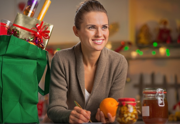 Portrait of happy young housewife with christmas shopping bag in - Fotografie, Obrázek