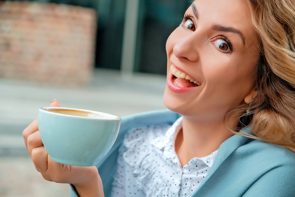 girl drinking coffee on the street. a cup of coffee. a cup of coffee and a girl's face close-up. - Foto, Imagen