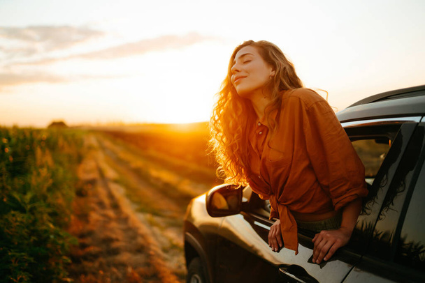 Towards adventure! Young woman is resting and enjoying the trip in the car.  Lifestyle, travel, tourism, nature, active life. - Photo, image