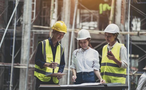 A diverse team of experts are planning on the construction site. Real estate project with civil engineers, architects, business investors and the general staff are discussing the details of the plans - 写真・画像