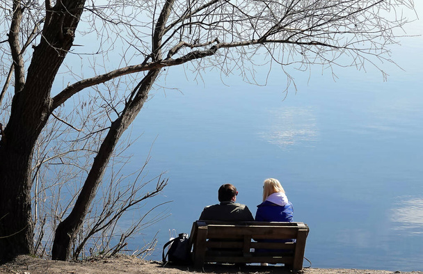 Kiev, Ukraine April 3, 2021: a man and a woman sit on the shore of the lake - Foto, Imagem