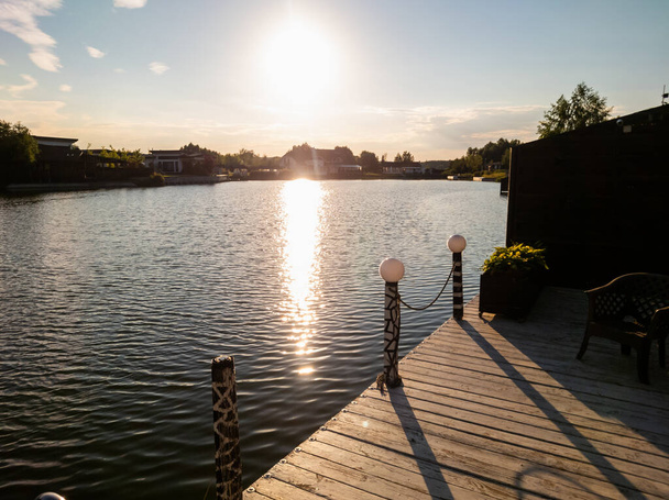 Empty wooden jetty overlooking a lake at sunset with the reflection of the fiery sun on the water - Foto, immagini