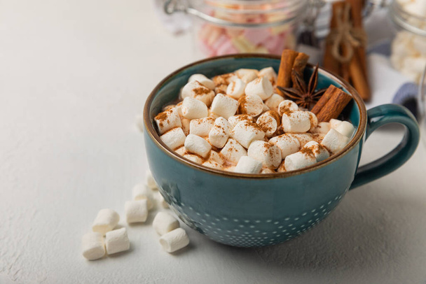 Cup of tasty cocoa drink and marshmallows in blue cup.Spices and marshmallows for winter drinks on white texture table.Winter hot drink.Hot chocolate with marshmallow and spices.Copy space. - Photo, Image