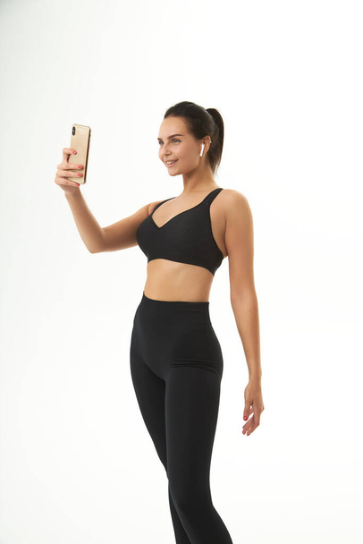 фітнес дівчина на тренуванні в спортивному одязі тримає смартфон в руках
 - Фото, зображення