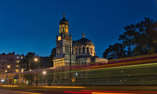 Τραμ, εκκλησία και σούρουπο. Lodz, Πολωνία - 2 Αυγούστου 2022 Θολή κίνηση του τραμ με φόντο την εκκλησία Alexander Nevsky στο απογευματινό τοπίο του Lodz. - Φωτογραφία, εικόνα