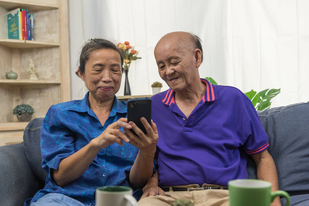 Азиатские пожилые люди с помощью мобильного телефона подключение к сети Интернет технологии связи в домашних условиях. - Фото, изображение