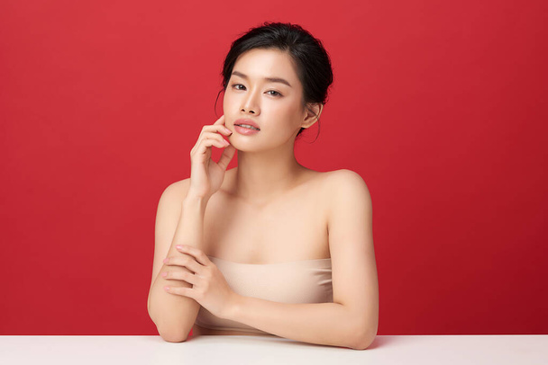 Belle jeune femme asiatique avec une peau propre et fraîche sur fond rouge, Soins du visage, Soins du visage, Cosmétologie, beauté et spa, Portrait de femmes asiatiques. - Photo, image