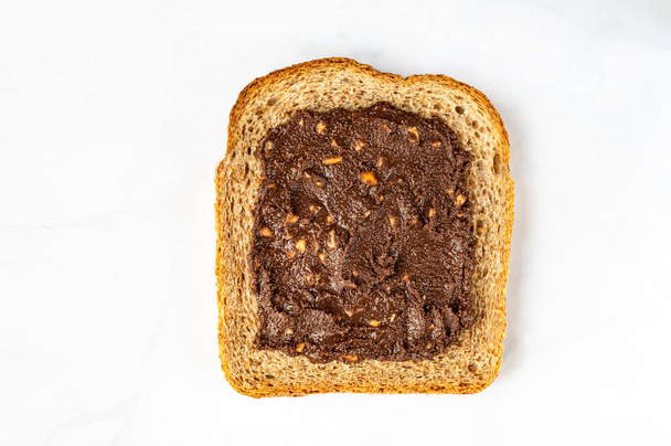 Slice of open sandwiche from wholegrain bread with chocolate crunchy almond butter, healthy snack option - Foto, afbeelding