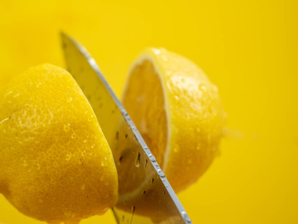 Cut the lemon with a knife in the air. Cut lemon with a knife. - Foto, Bild