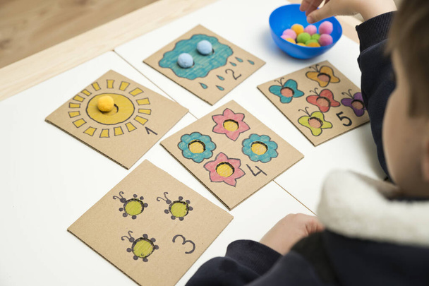 Hand made children home activity from cardboard and pom poms. Early education, Montessori methodology. Implement to develop fine motoric skills, logical thinking learn counting. - Valokuva, kuva