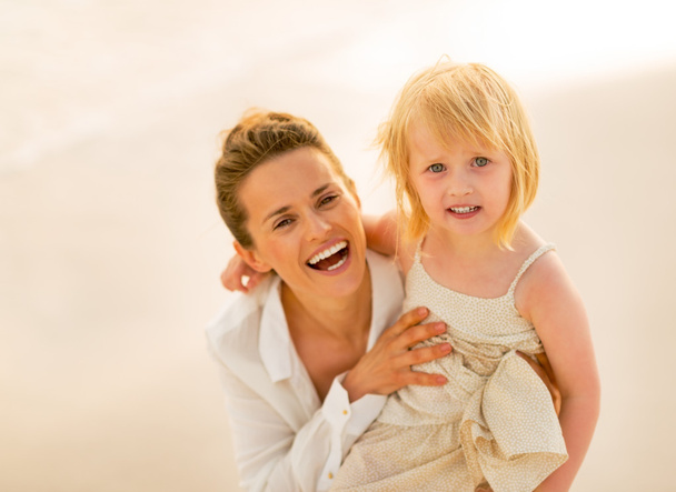 Portrait of smiling mother and baby girl on the beach in the eve - Foto, Bild