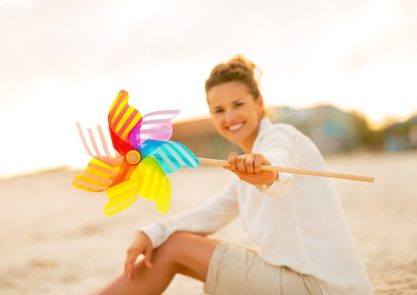 Closeup on young woman showing colorful windmill toy while sitti - Photo, Image