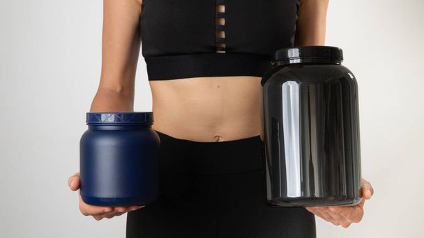 Uma mulher de uniforme desportivo tem nas mãos uma lata de proteína e bcaa. Foto de alta qualidade - Foto, Imagem