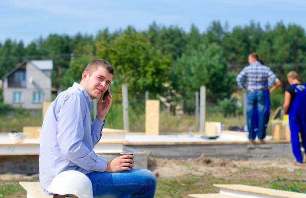 Young builder chatting on his mobile - Valokuva, kuva
