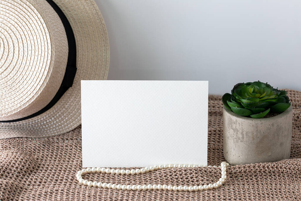 Blank white invitation card in landscape lay on knitted cloth with beach hat and pearl lace. - Foto, Bild