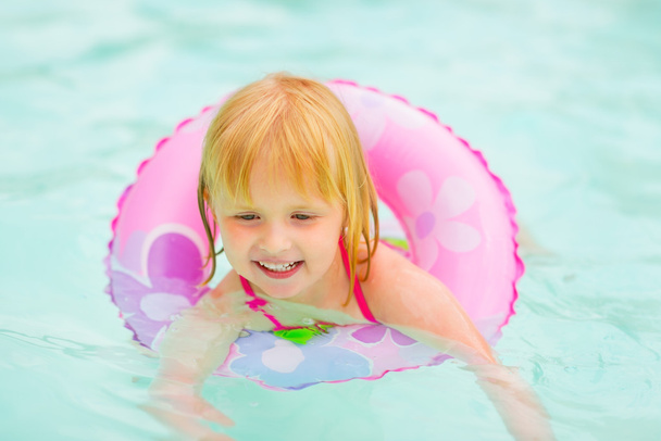 Portrait of baby girl with swim ring swimming in pool - Foto, Imagen