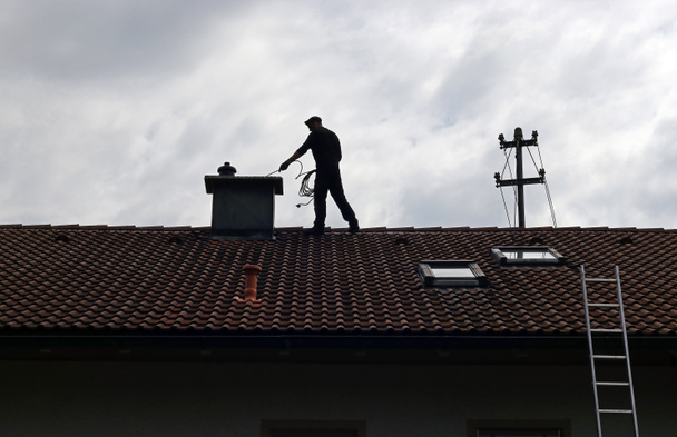A chimney sweep cleans the chimney on a house roof - Foto, Bild