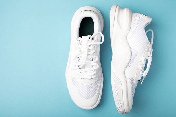 White sneakers on a blue background.Fashion.UNISEX. Sneakers are sports shoes for an active lifestyle. Product photo and levitation concept. Street style. Copy space. Place for text. - Fotó, kép