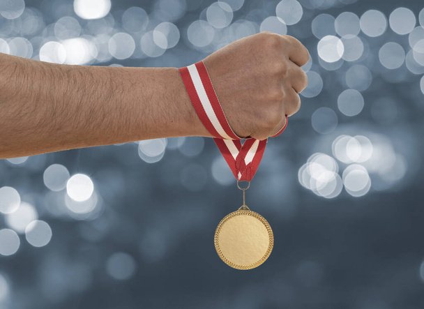 Man raising hand and holding gold medal. Concept of ambition perseverance and victory. - Zdjęcie, obraz