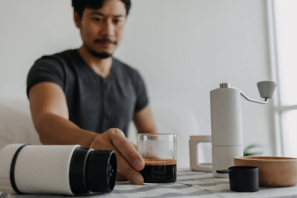 Asian man make and drink his own french press coffee. - Zdjęcie, obraz