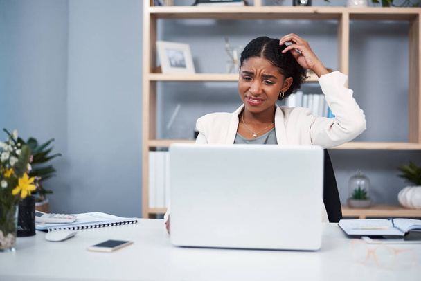 Confused, stressed and angry business woman reading email and scratching her head thinking in her office. A young African American corporate female annoyed while working on a laptop at her workplace. - Foto, Imagem