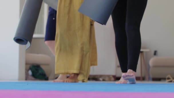 Three women walks in the studio and puts down yoga mats on the floor. Mid shot - Filmati, video