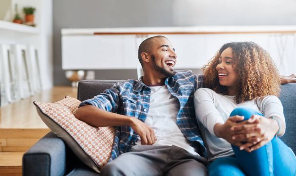 Happy, relaxed and carefree couple bonding on the couch together at home. Loving, affectionate and smiling boyfriend and girlfriend relaxing in the living room. Sitting down and enjoying the weekend. - Foto, imagen
