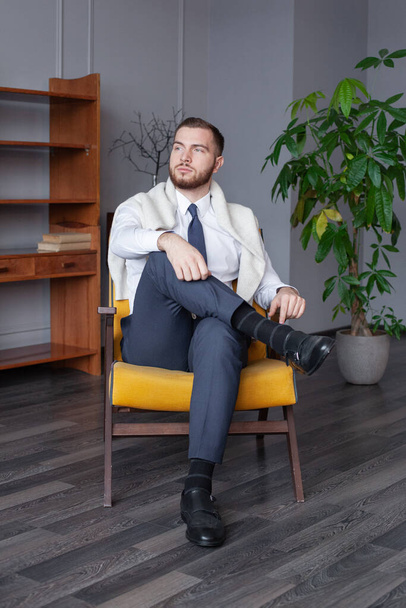 Молодой бизнесмен сидит в помещении - Фото, изображение