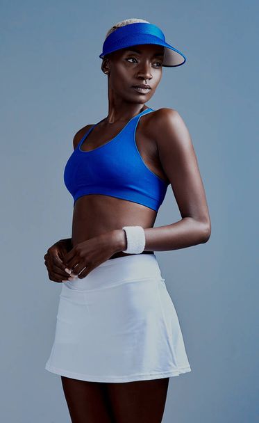Одевайся и приходи. Студийный снимок спортивной девушки в теннисной форме, позирующей на сером фоне - Фото, изображение