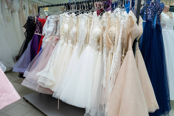 Много различных вечерних платьев и свадебных платьев на вешалке в магазине. - Фото, изображение