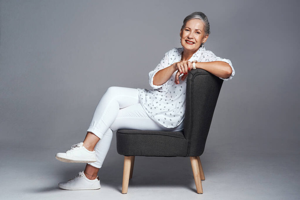 You have every right to make it all about you. Studio shot of a senior woman sitting on a chair against a grey background - Foto, Bild