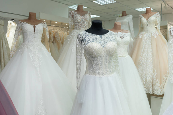 A close-up of a wedding dress against the background of other wedding dresses in a bridal salon. - 写真・画像