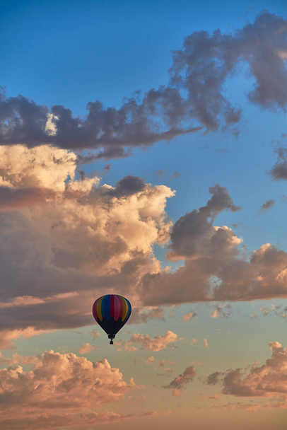 A hot air balloon at sunset with looming storm clouds in the background. - 写真・画像