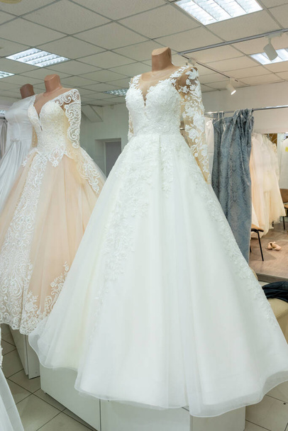 Beautiful wedding dresses in a bridal boutique on mannequins. - Fotó, kép