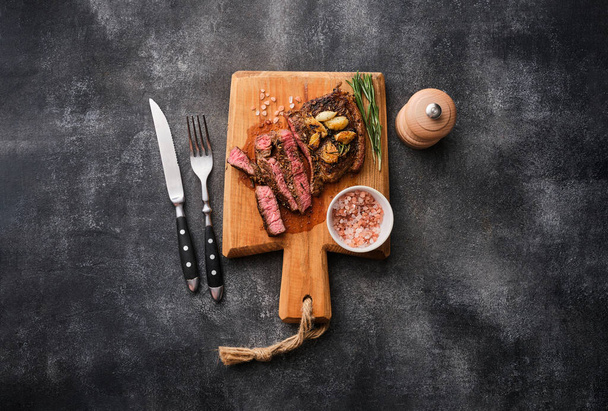 Rib eye steak. Medium rare Ribeye steak or beef steak on the wooden tray with garlic - Foto, afbeelding