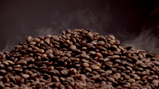 Duftender Rauch aus gerösteten Kaffeebohnen aus nächster Nähe. Leichter Dampf steigt in Superzeitlupe über Haufensamen auf. Frische braune Körner für das morgendliche Energiegetränk. Tolles Aroma von Kaffee-Konzept. - Filmmaterial, Video