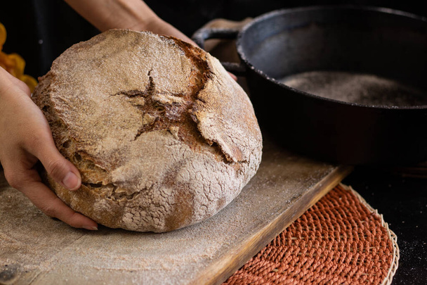 female hands with sourdough bread on wooden table - Fotografie, Obrázek