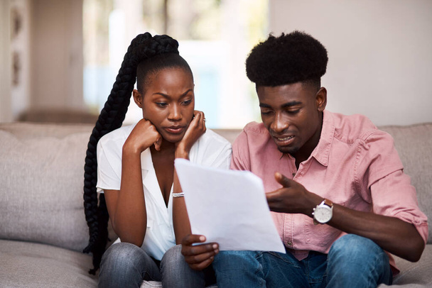 How are we going to afford this. a young couple looking stressed while going over paperwork at home - Foto, immagini