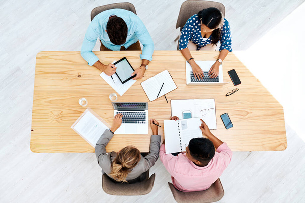 Процесс идеи. Высокоуровневый снимок группы бизнесменов, работающих вместе за столом в офисе - Фото, изображение