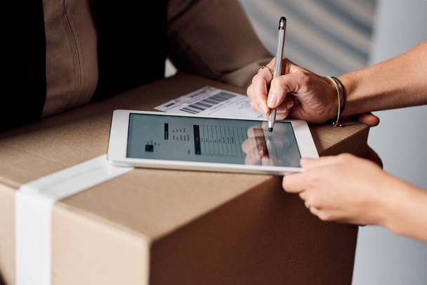 All we need is your digital signature. Closeup shot of an unrecognisable woman using a digital tablet to sign for a delivery from the courier - Foto, imagen