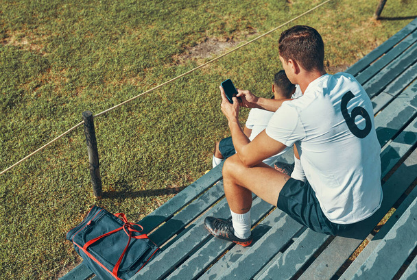 Missed the game Catch up online. a rugby player using his cellphone while sitting on the bench - Foto, immagini