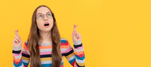 schoolgirl nerd child in eyeglasses for vision cross fingers making a wish, wish. Child face, horizontal poster, teenager girl isolated portrait, banner with copy space - Foto, Imagem
