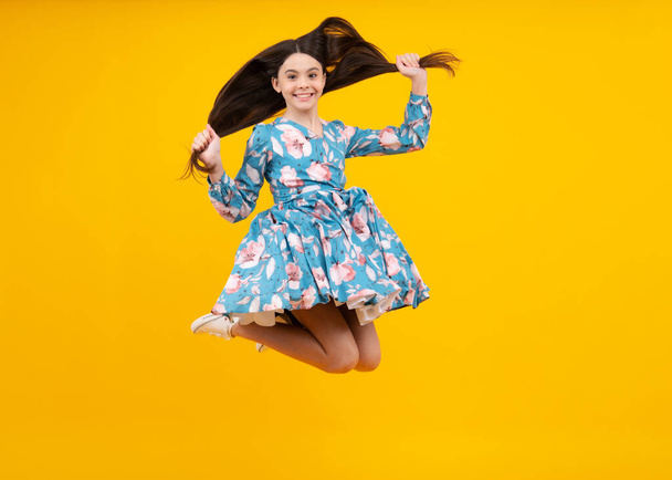 Happiness, freedom, motion and child. Young teenager girl jumping in air over yellow background. Excited face. Amazed expression, cheerful and glad - Photo, Image