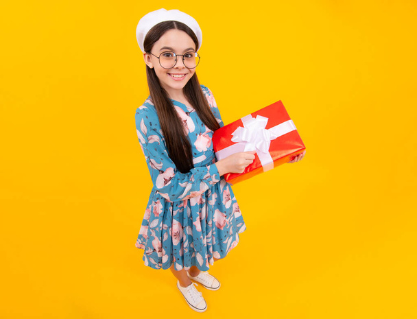 Child with gift present box on isolated studio background. Gifting for kids birthday. Happy teenager, positive and smiling emotions - Zdjęcie, obraz