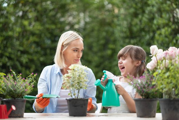 Mother and little girl helping to care for plants and flowers at outdoor together. - Φωτογραφία, εικόνα