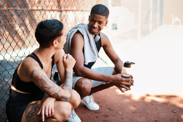 Just happy to be hanging. two sporty young people chatting to each other against a fence outdoors - Fotoğraf, Görsel