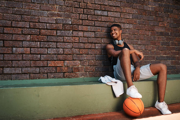I believe in shooting for your goals. a sporty young man taking a break after a game of basketball - Фото, изображение
