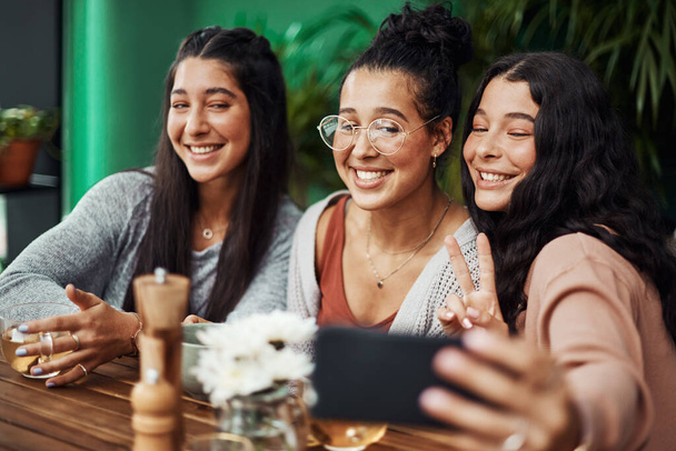 Sister time is selfie time. young sisters taking selfies together at a cafe - Photo, image